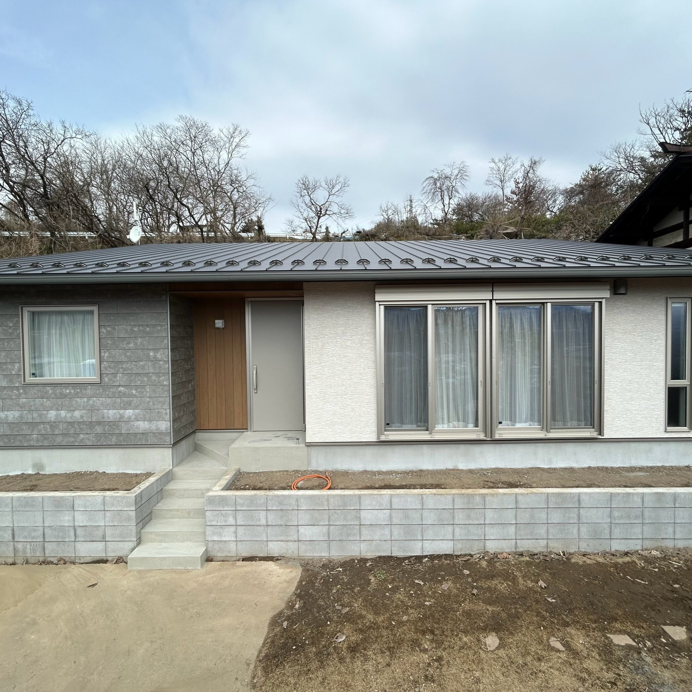 落ち着いた2色の外壁に、木目の玄関がアクセントになった平屋で...